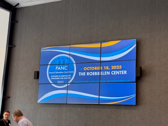 Indoor conference display panel on wall with event details and two people nearby