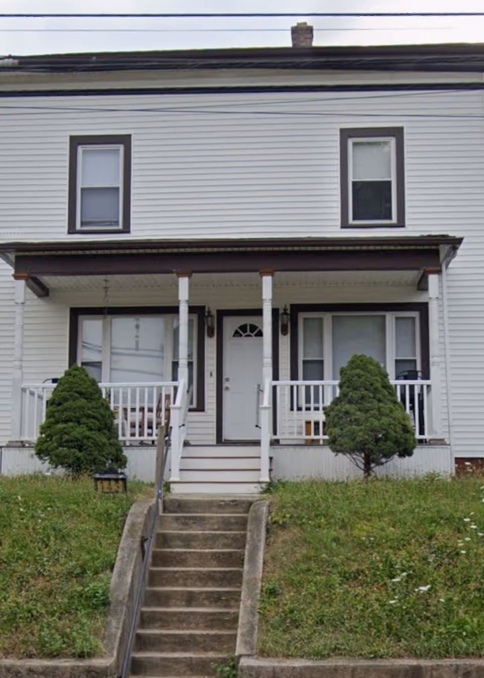 Two-story white house with a small front porch and central entry.