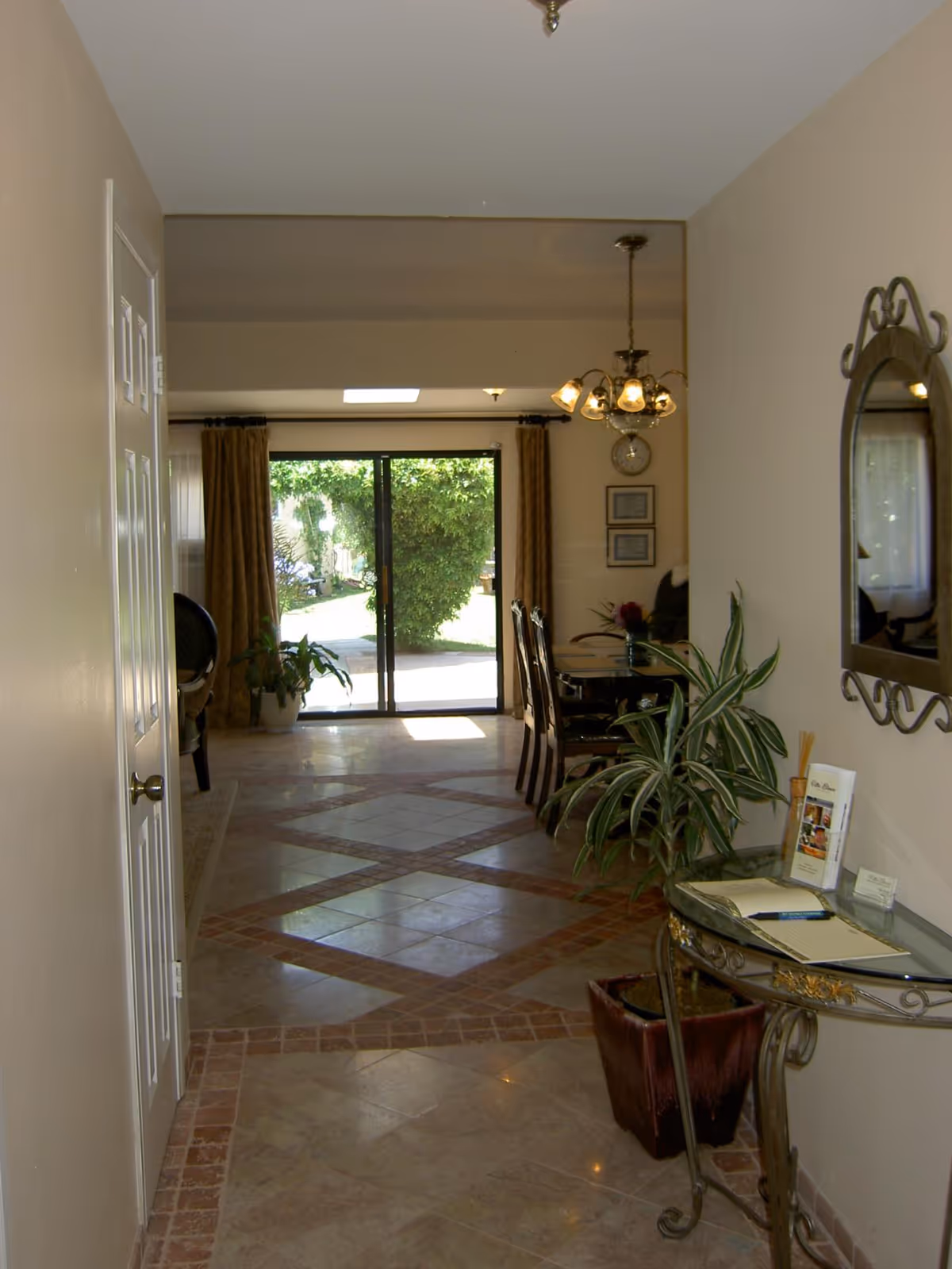 Foyer hallway opening to a dining area with glass doors and potted plants