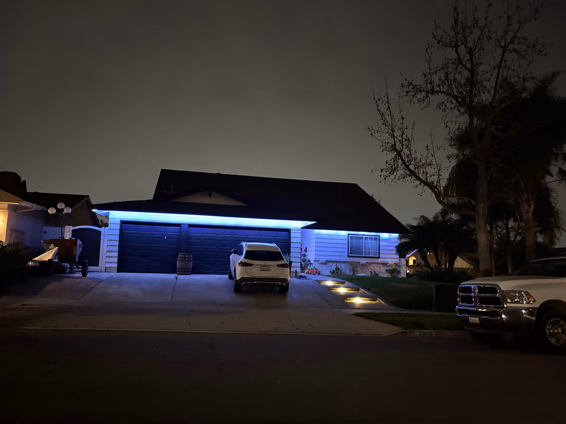 Night view of a single-story building with blue-lit front and parked cars
