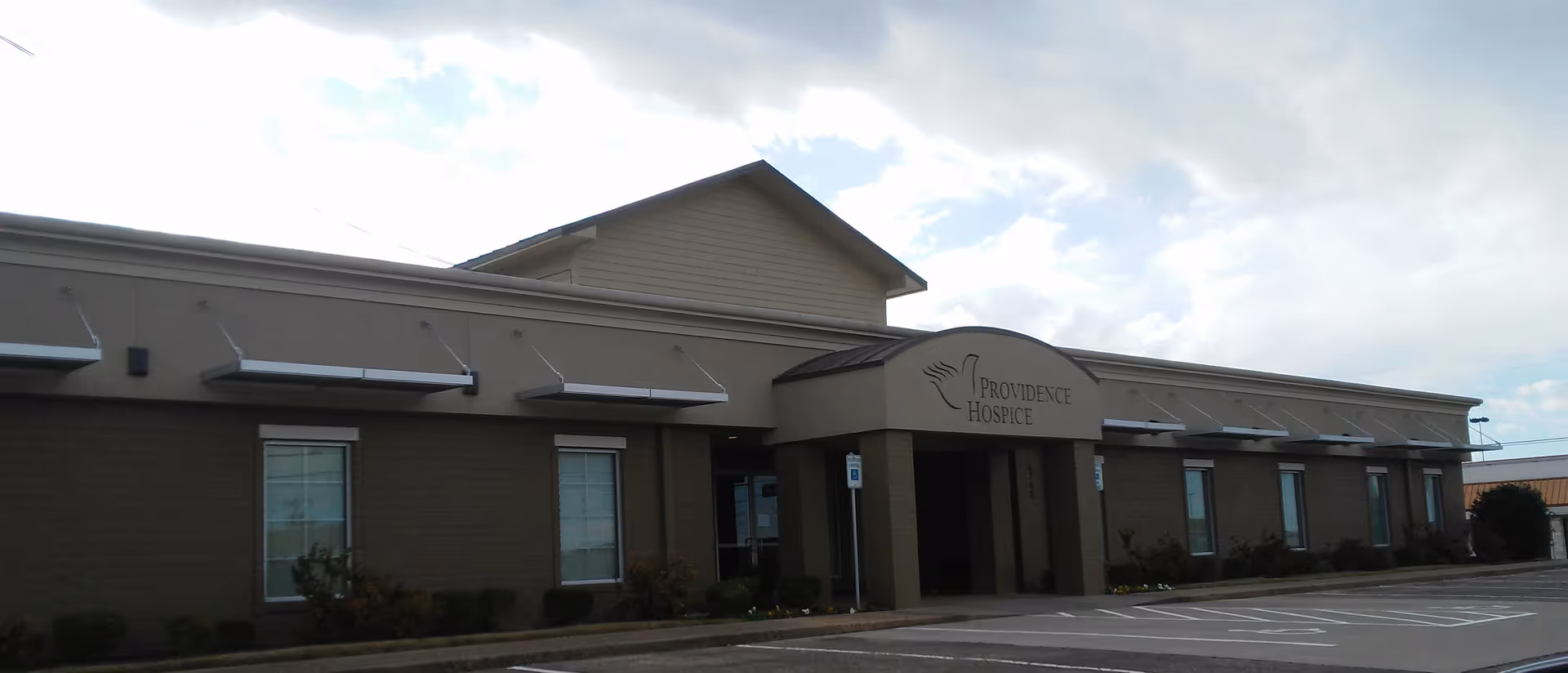 Exterior view of Providence Hospice building with a parking lot and entrance.