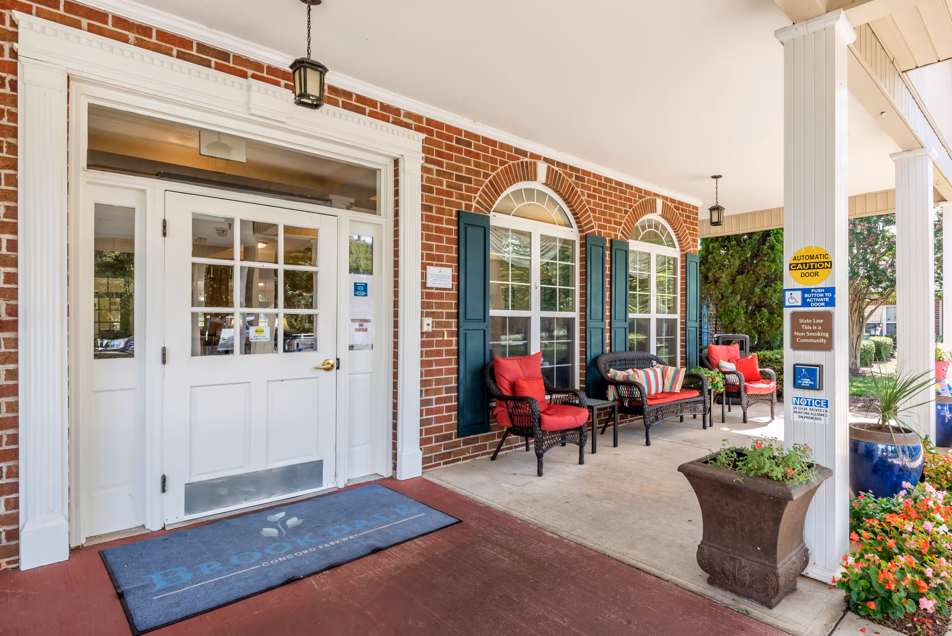 Front entrance of Brookdale Concord Parkway with brick facade, arched windows, and red-cushioned seating.