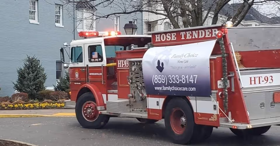 Red fire truck labeled Family Choice Home Care parked outside a blue building.