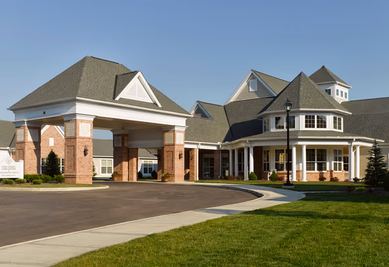 Exterior view of a brick senior living facility with a porte-cochère entrance.