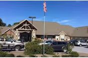 Exterior view of Twin Pines Health Care Center with cars parked in front and American flag