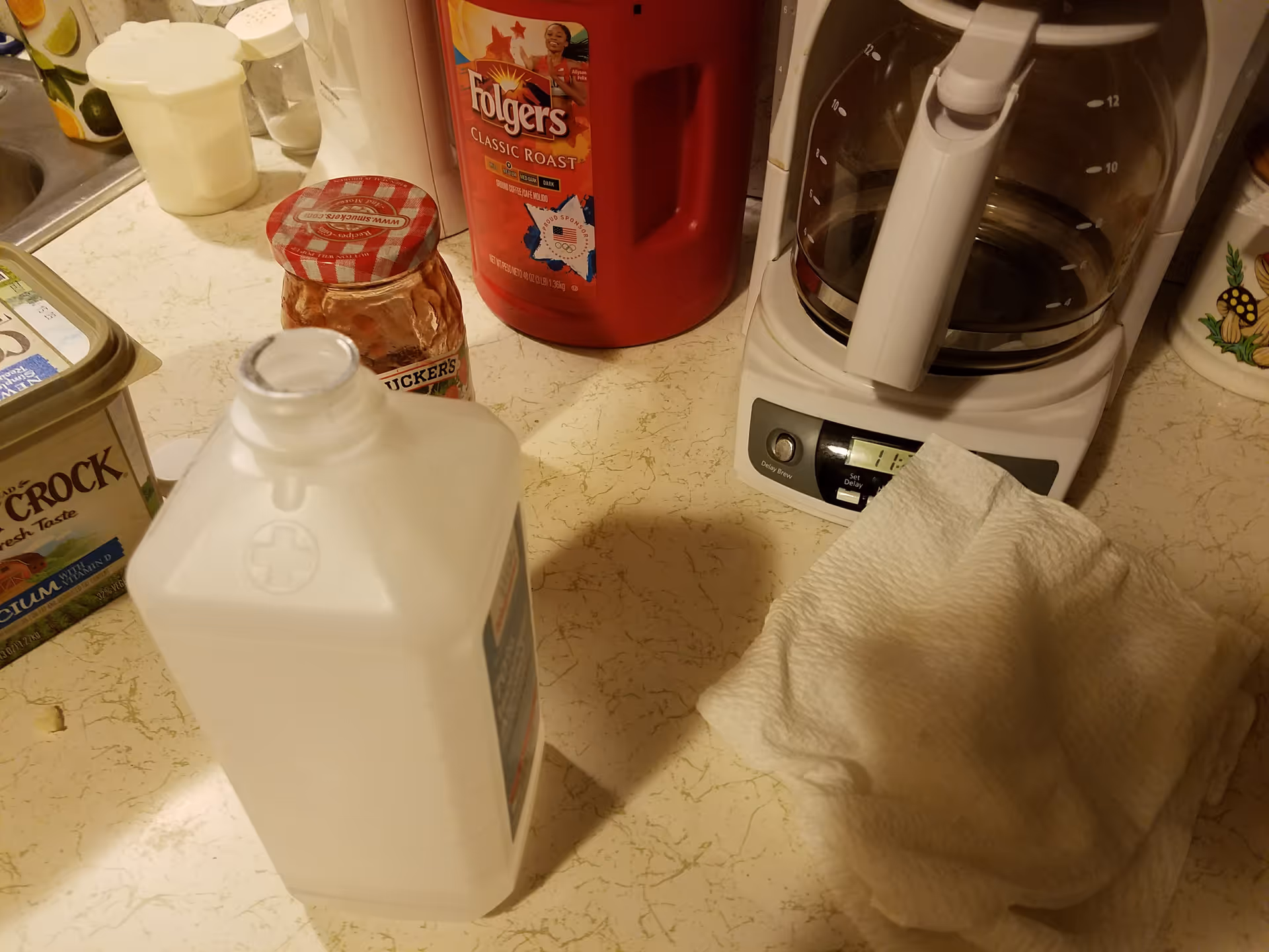 Kitchen counter with a coffee maker, jam jar, white jug, and cleaning bottle.