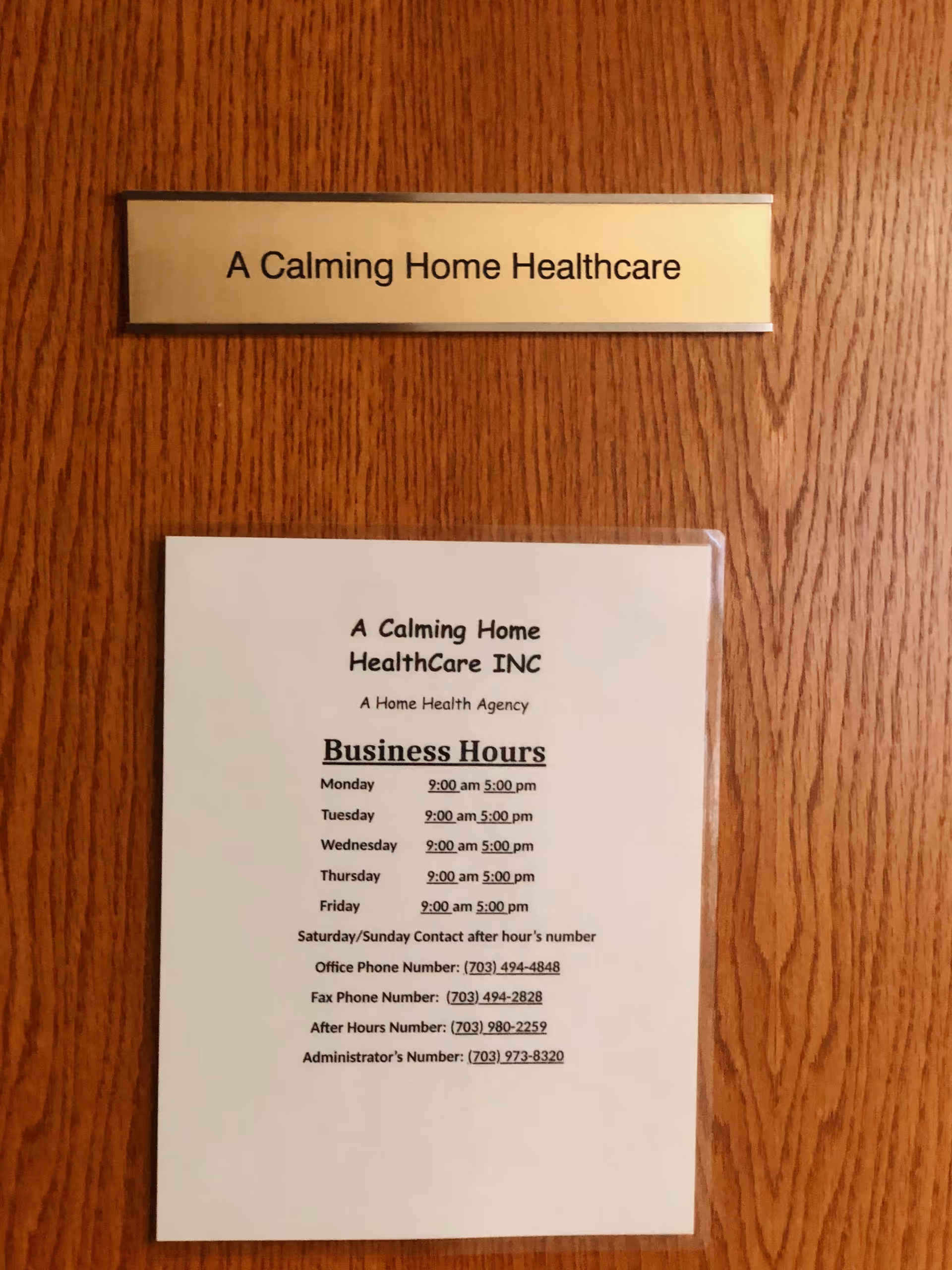 Wooden door with a nameplate reading A Calming Home Healthcare and an hours sheet.