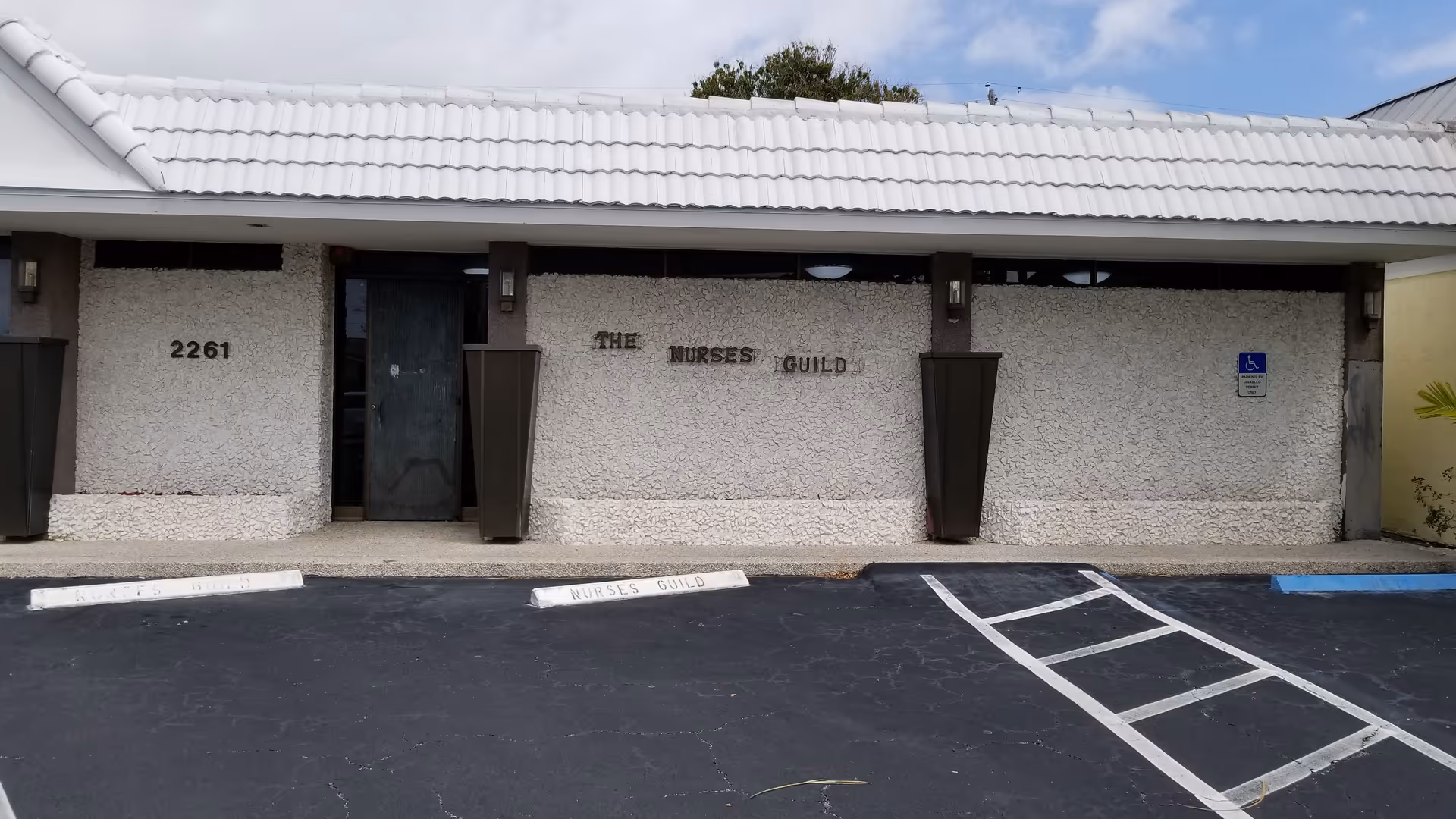 Exterior view of a nursing facility front with textured wall and Nurses Guild sign.