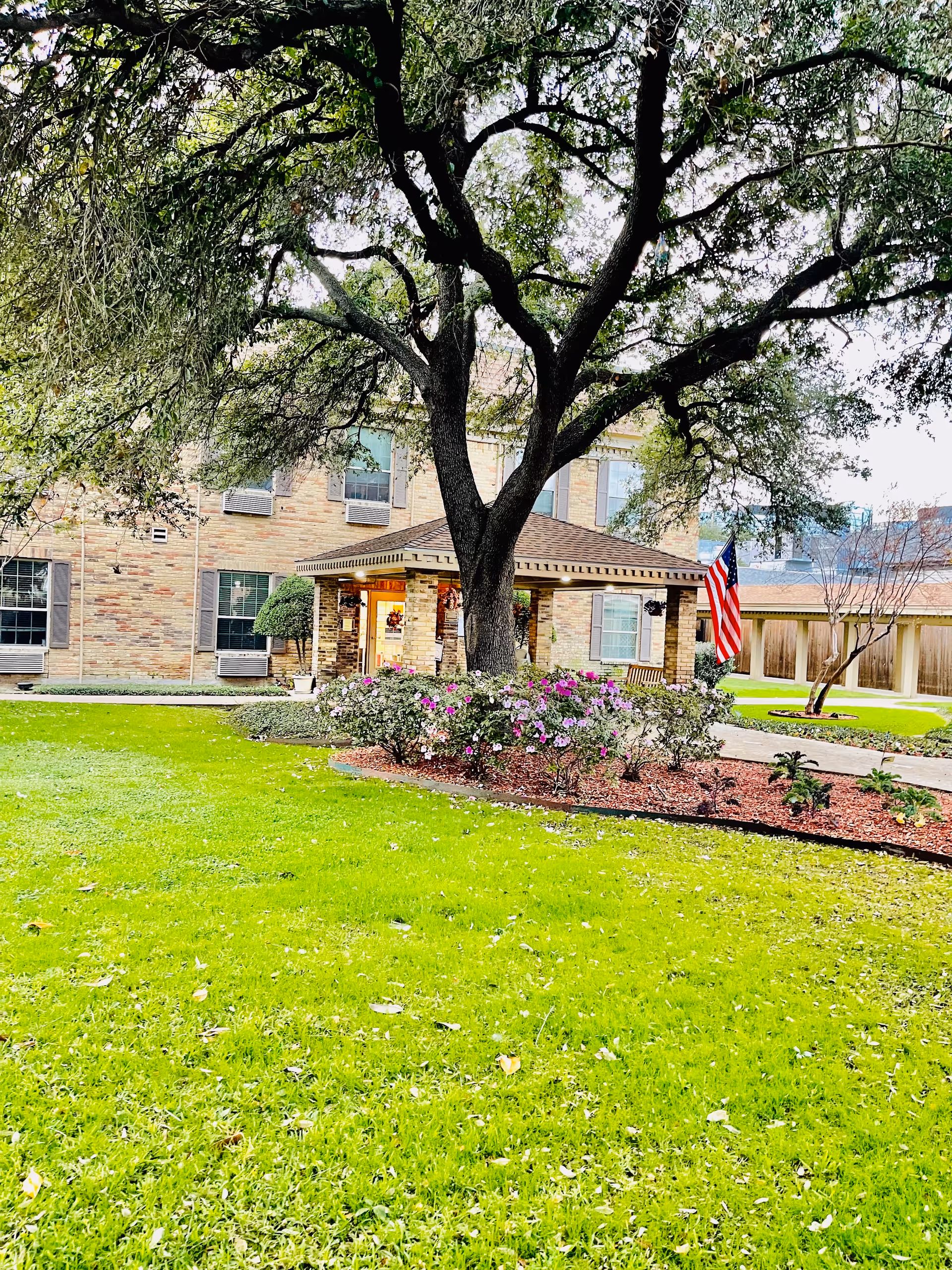 Front exterior of Emerson on Harvest Hill with a tree, lawn, and flag.