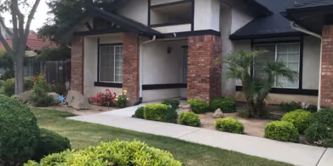 Exterior view of a Graysful Living facility with brick columns and landscaped front yard.