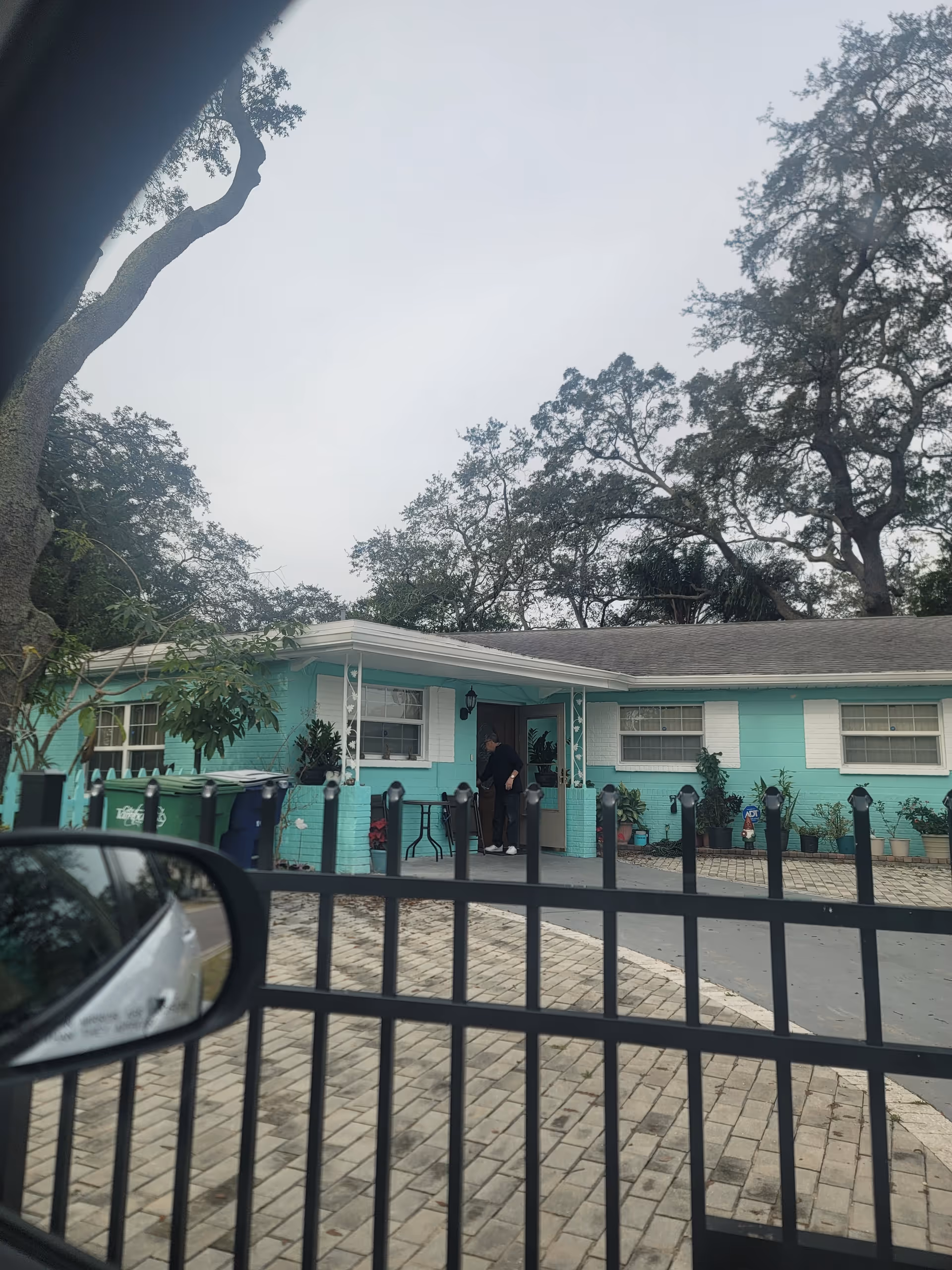Teal single-story facility exterior with entrance and surrounding potted plants.