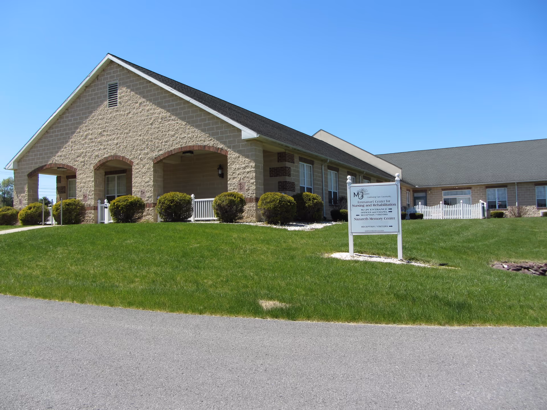 Front exterior of the Emmanuel Center for Nursing building with a manicured lawn and an entrance sign.