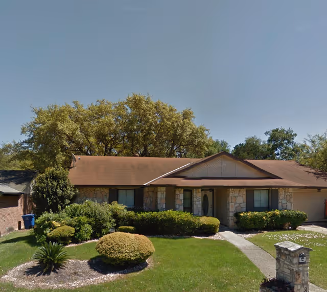 Single-story senior living facility exterior with stone facade and neatly landscaped front yard.