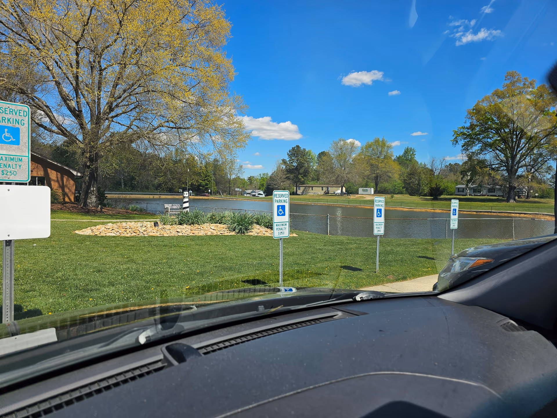View from a car windshield of Autumn Care of Biscoe's outdoor grounds by a pond.