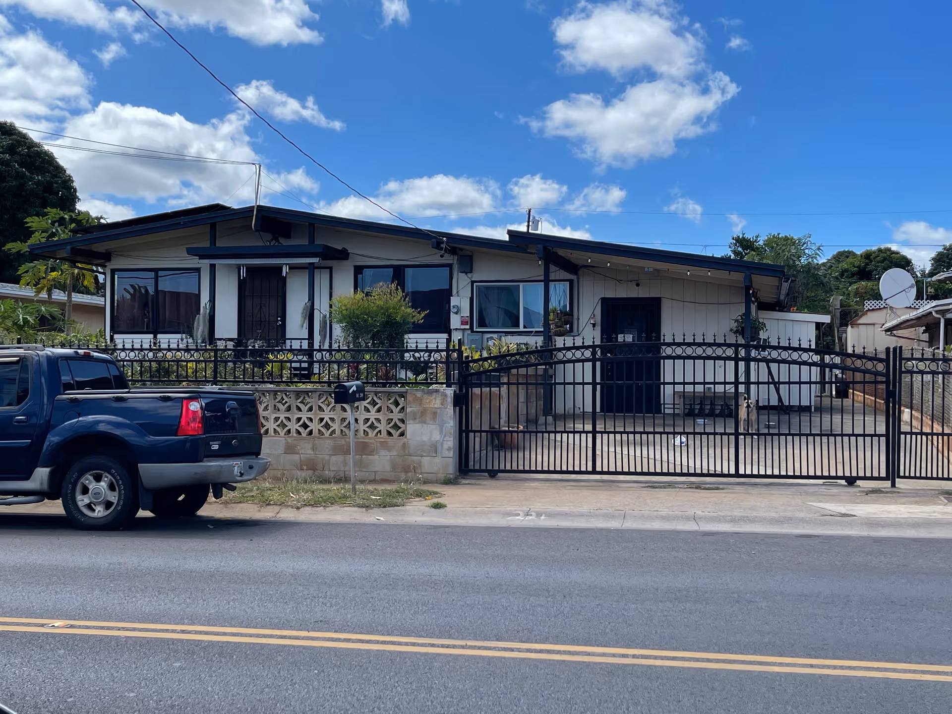 A single-story senior care facility behind a black gate with a blue pickup truck.