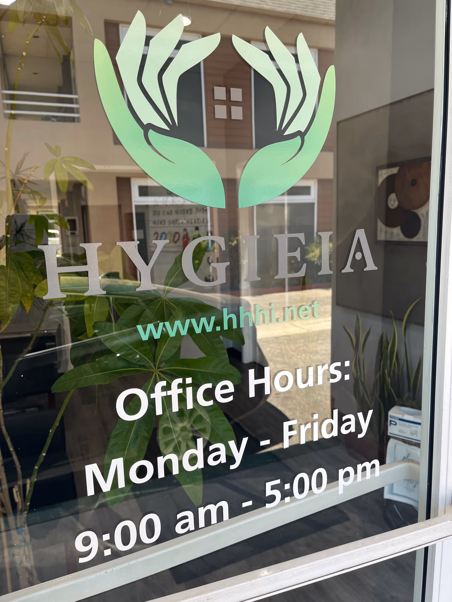 Glass storefront window showing Hygieia logo and office hours text.