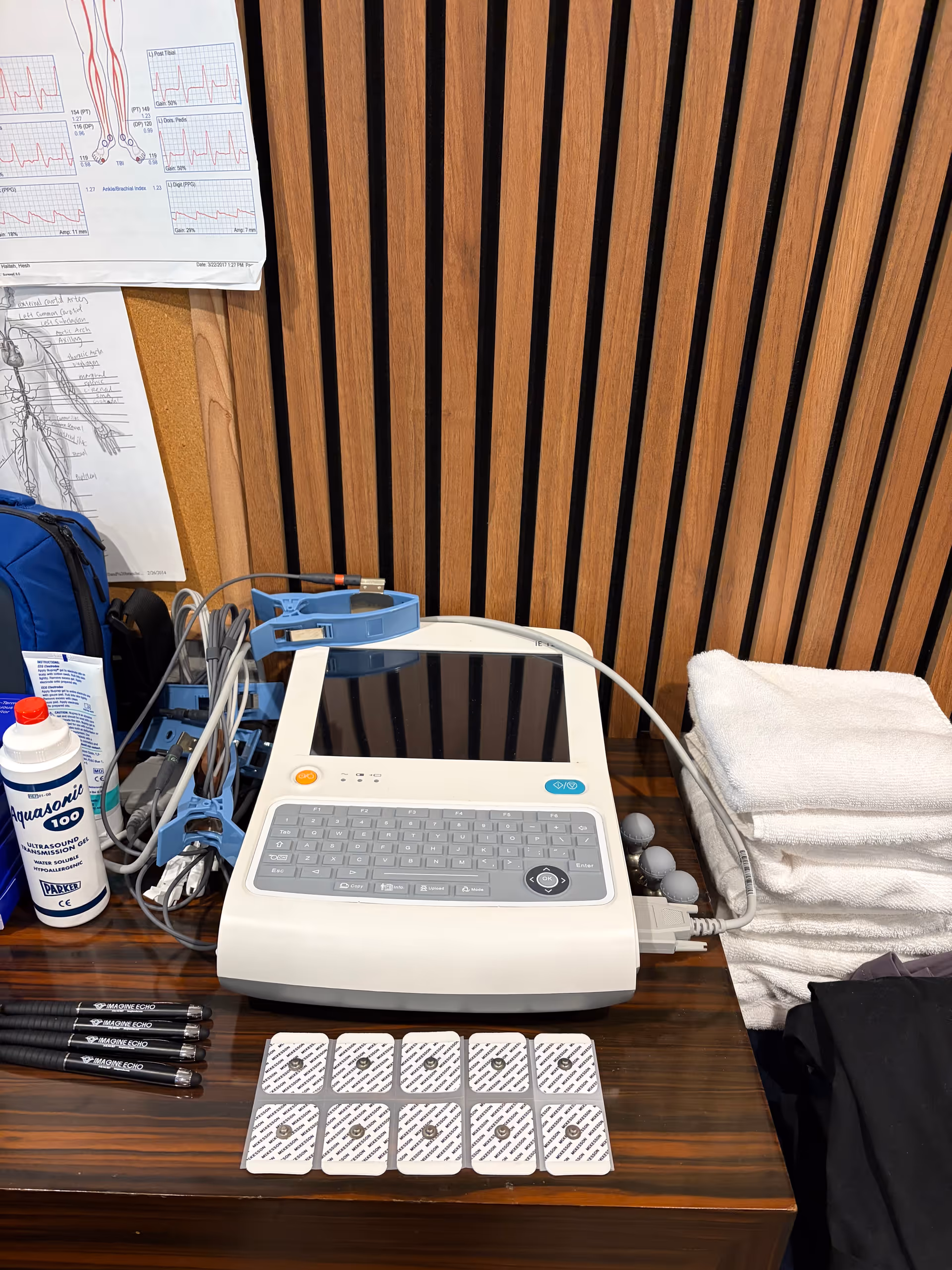 Medical equipment on a desk with towels and charts against wood-paneled wall.