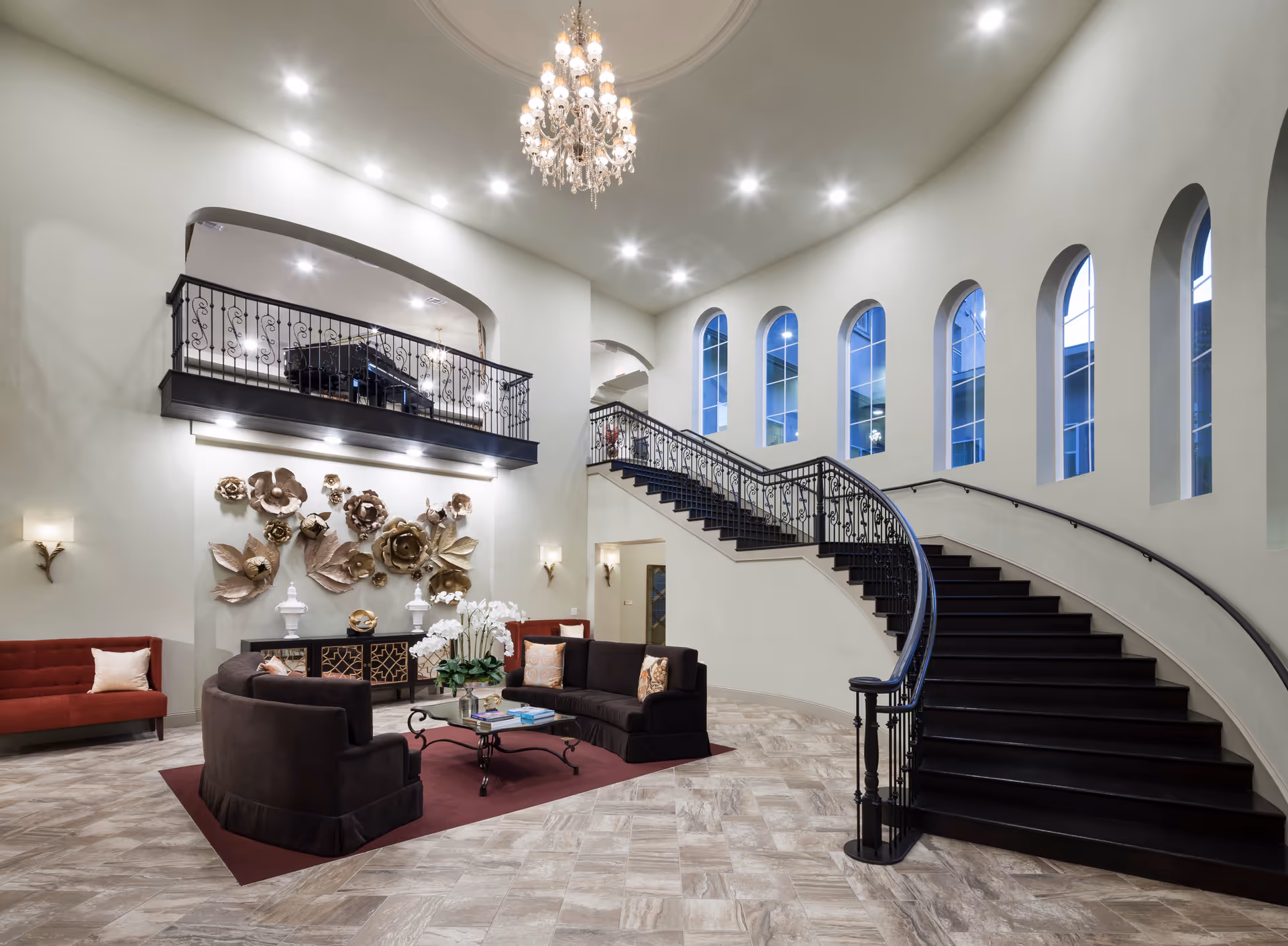Elegant hotel lobby with a grand curved staircase, chandelier, and seating area.