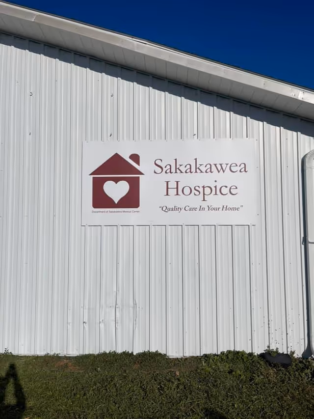 White metal building exterior with Sakakawea Hospice sign and heart logo.
