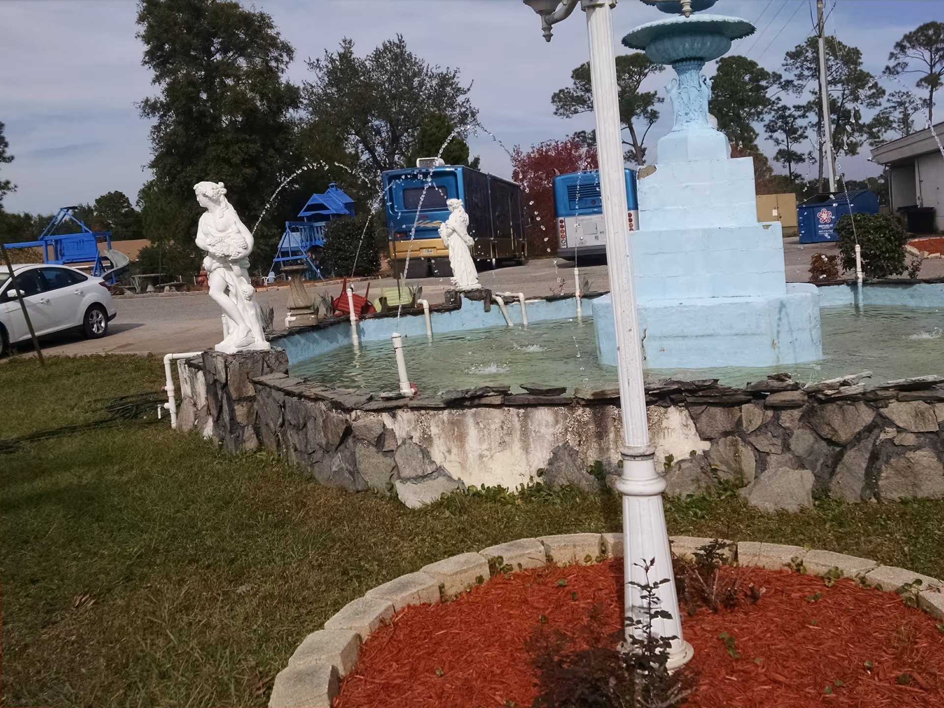 Blue fountain with statues in a landscaped outdoor area at Westpointe Retirement Community.
