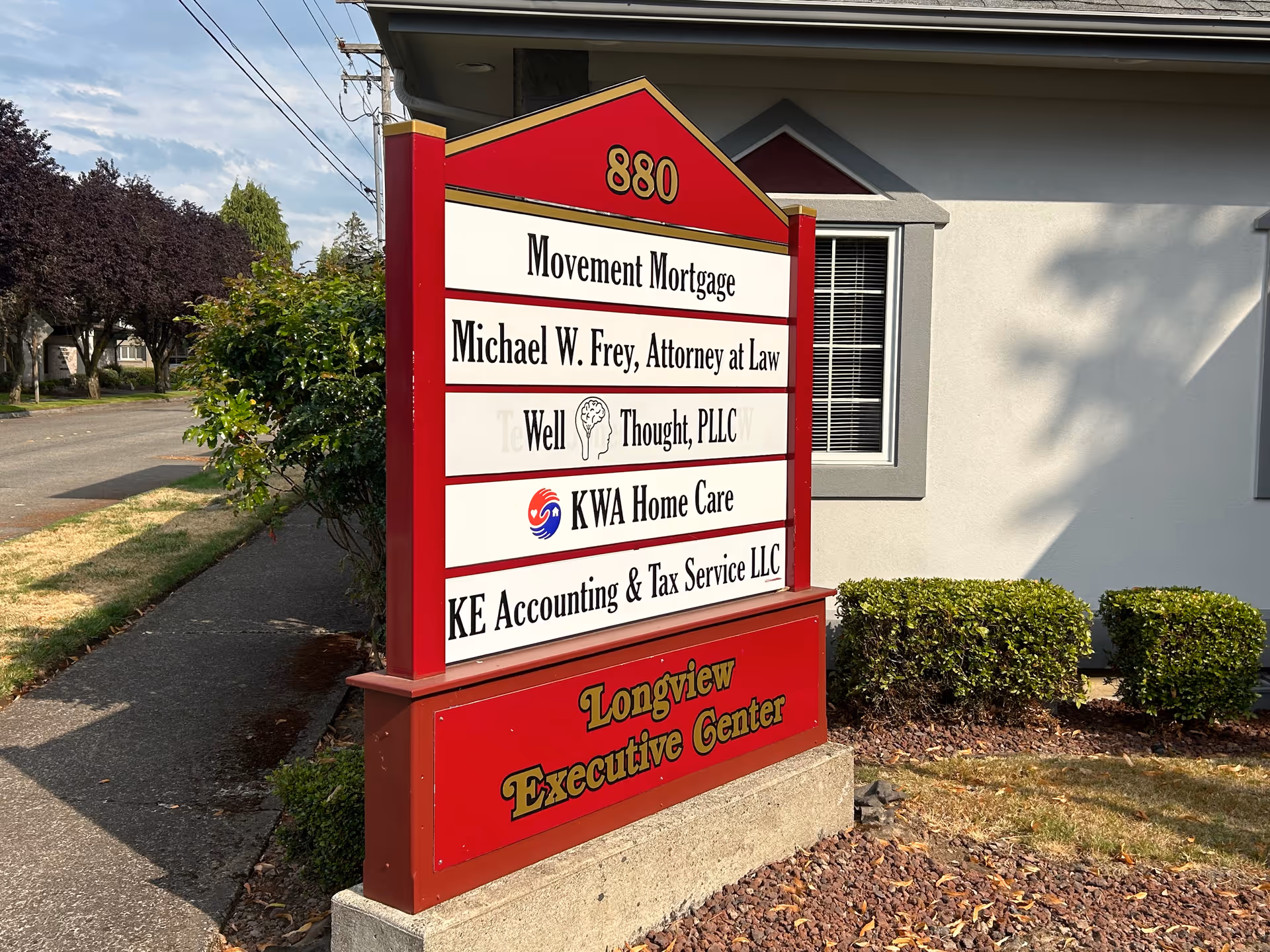 Outdoor signboard listing multiple businesses in front of a beige building