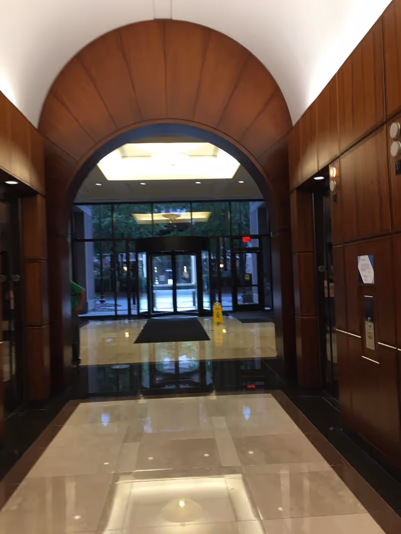 Wood-paneled arched lobby with glass doors and polished marble floors.