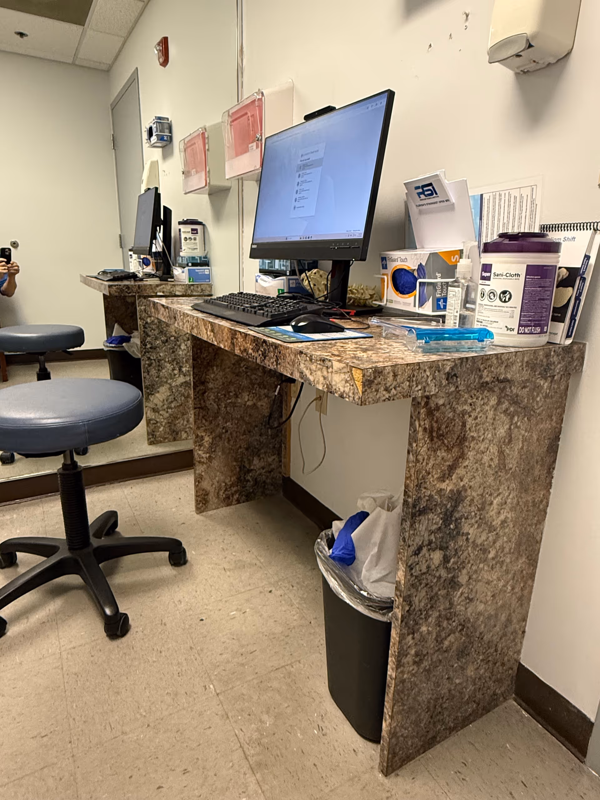 Marble reception desk with computer monitor and medical supplies inside a clinic.