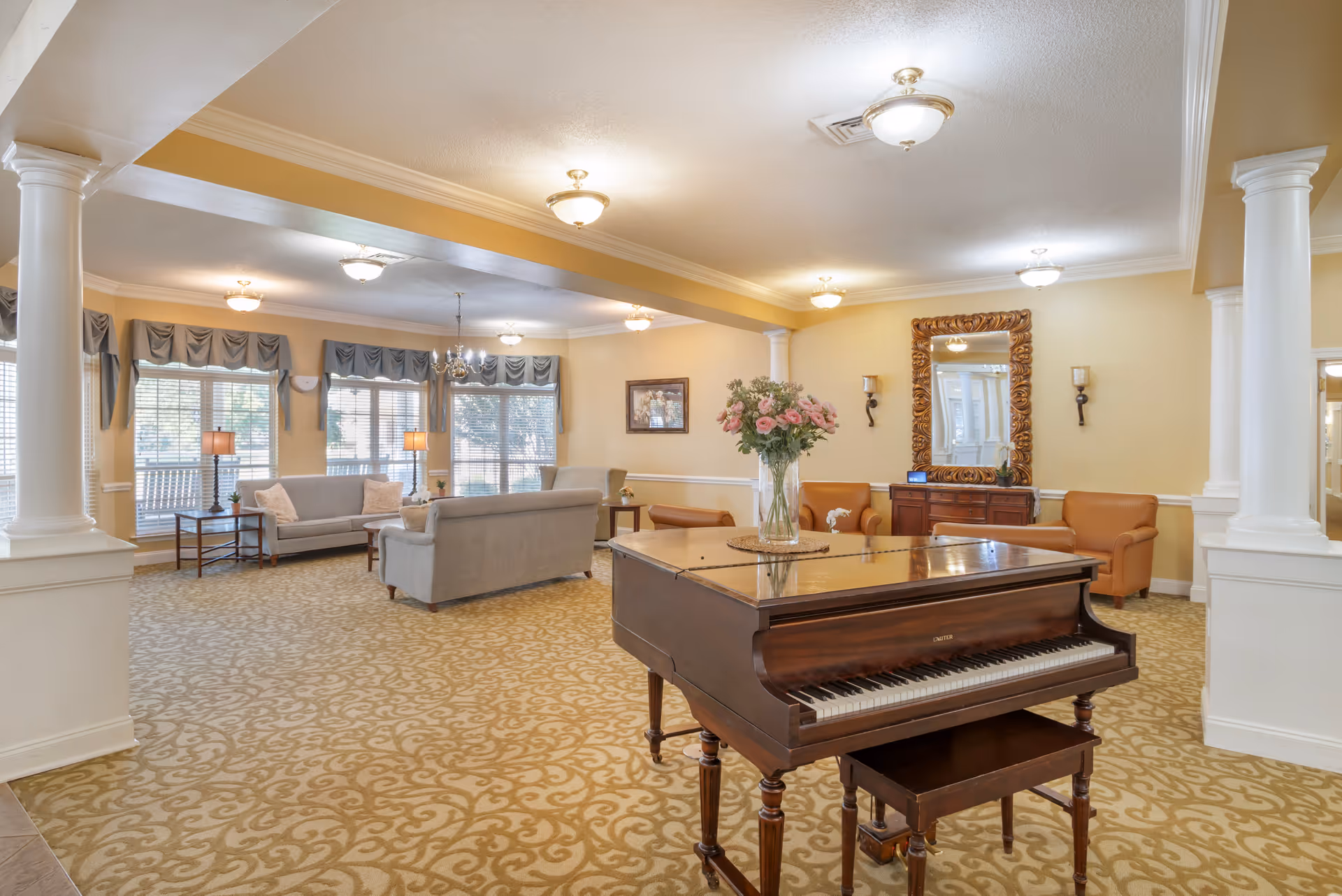 Spacious living room with grand piano, sofas, lamps, and decorative mirrors in a warm lounge.