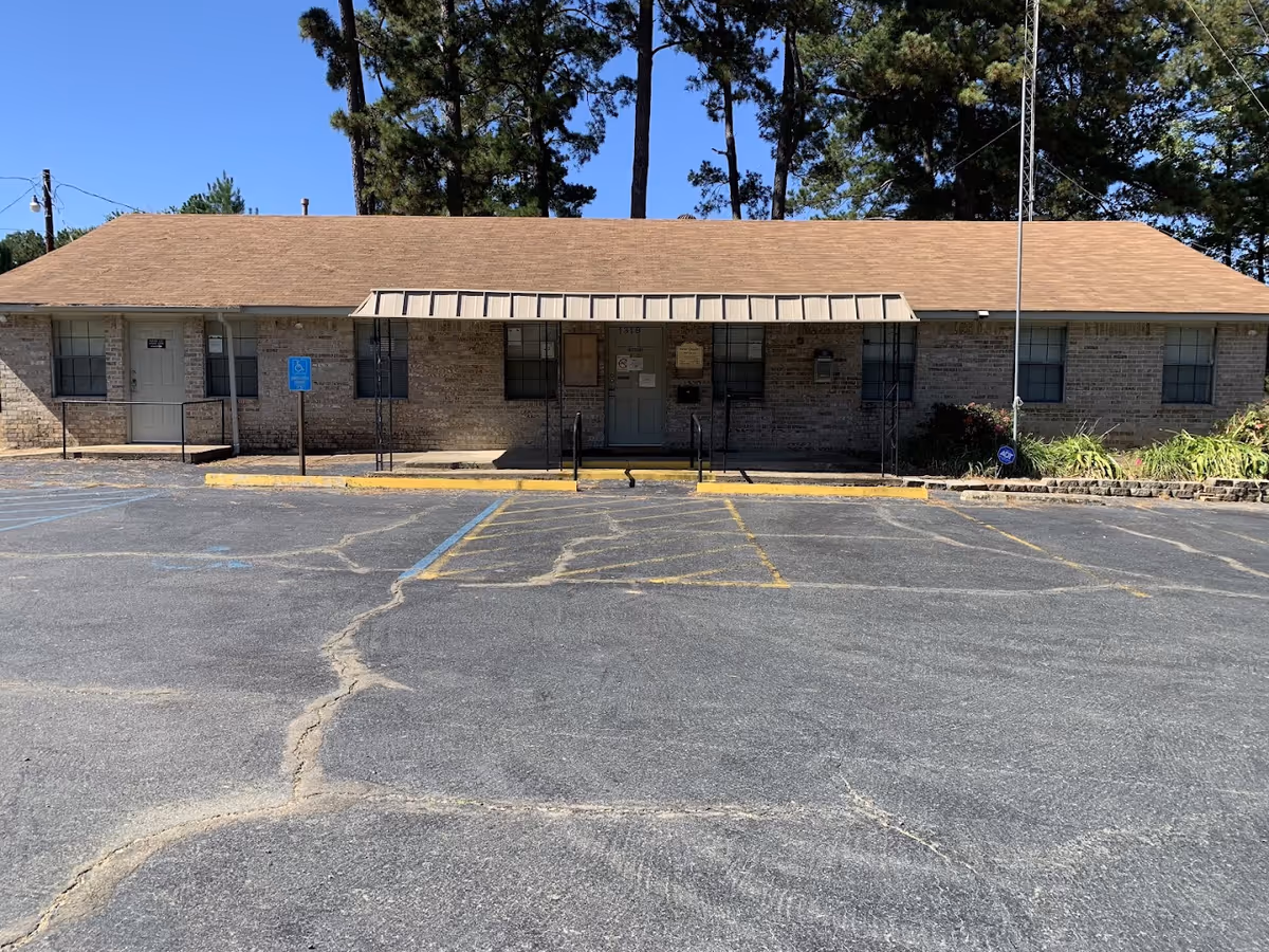Single-story brick senior living facility with a covered entrance and empty parking lot.
