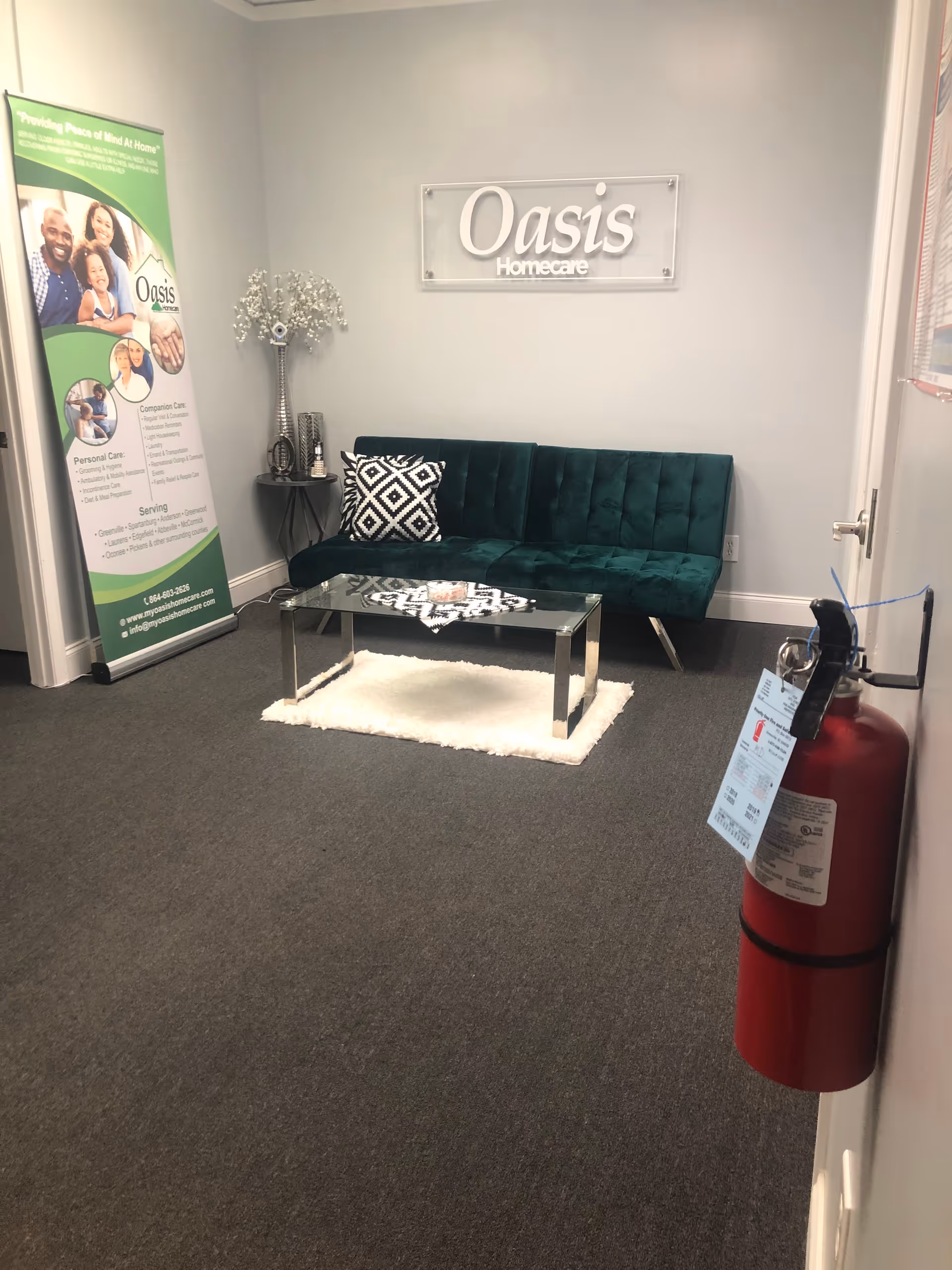 A small lobby area with green sofa, glass coffee table, and Oasis Homecare sign.
