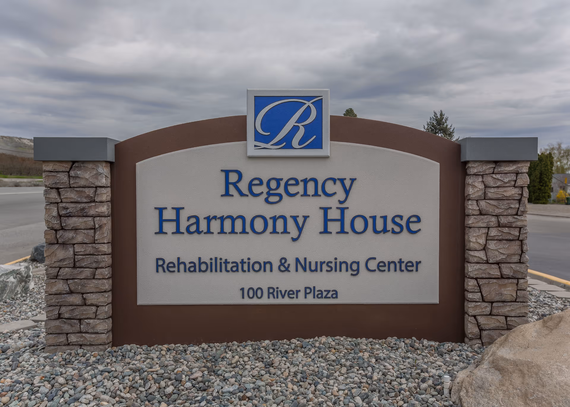 A front sign for Regency Harmony House Rehab & Nursing Center with stone pillars.