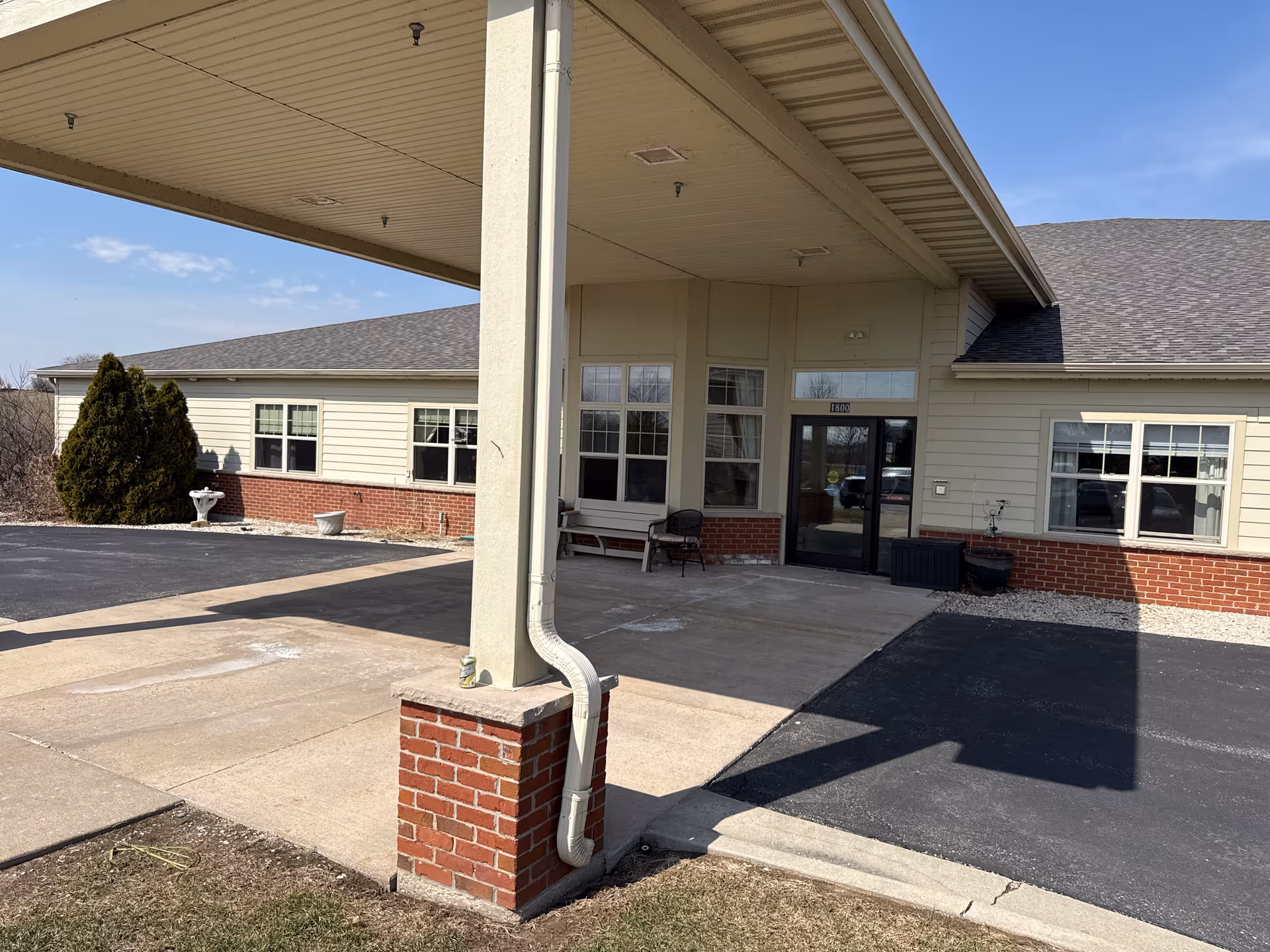 Exterior view of High Point Residence Port Washington entrance with a covered drop-off area.