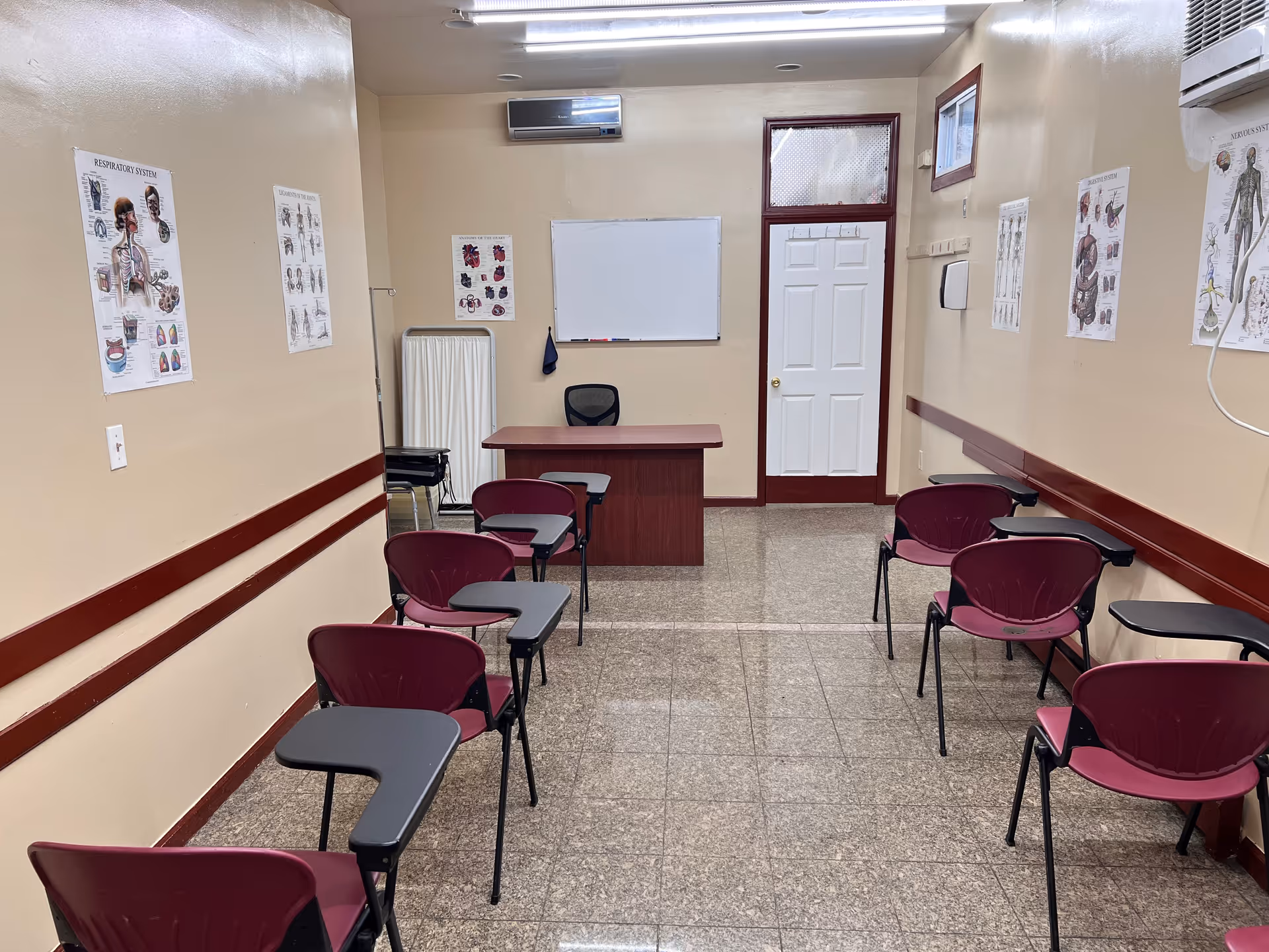 A small classroom in a senior facility with chairs, a desk, whiteboard, and posters.