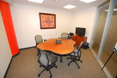 Small conference room with round table, chairs, red pillar, and glass divider.