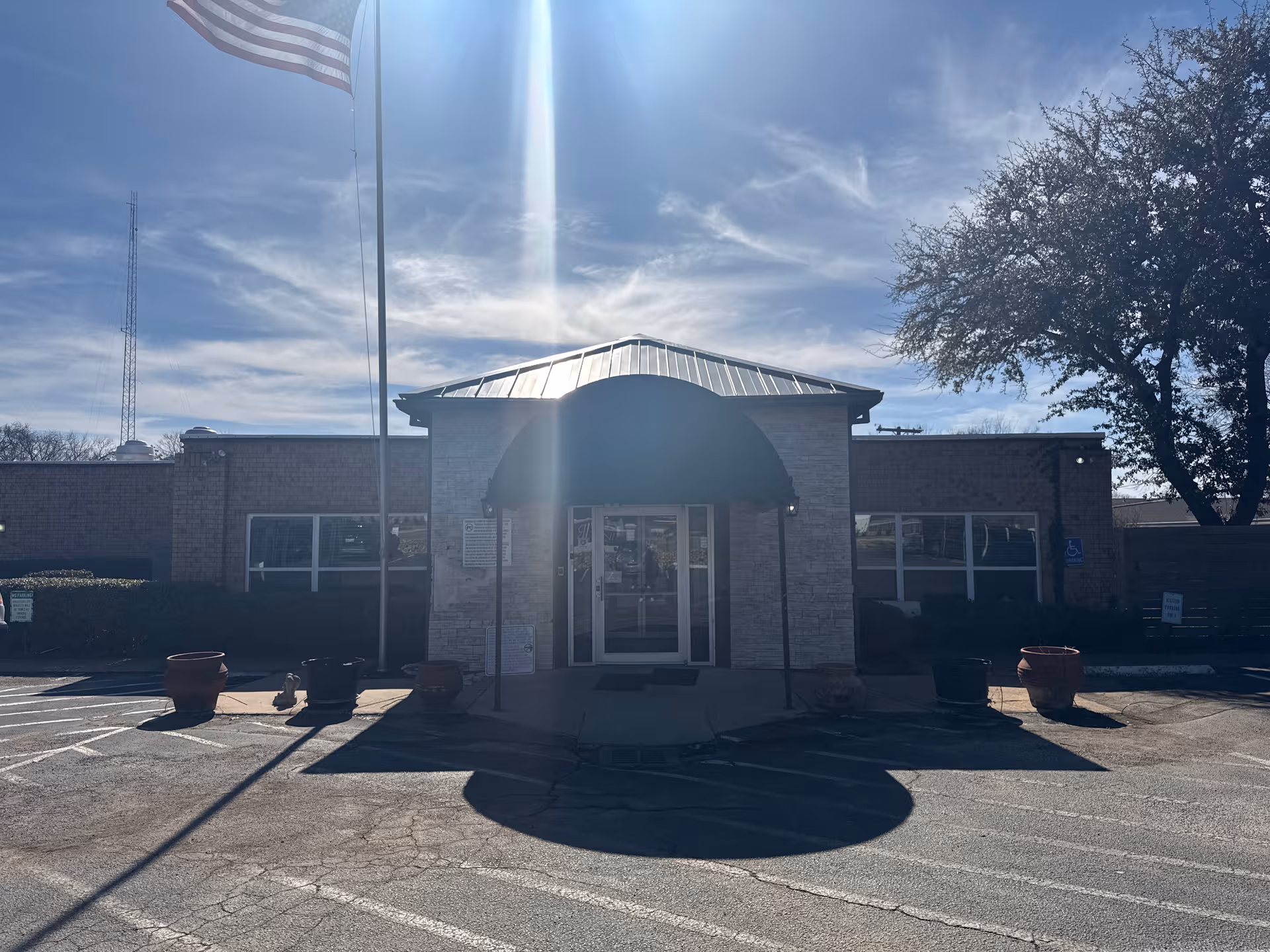 Front view of Birchwood of Richland Hills entrance with awning and American flag
