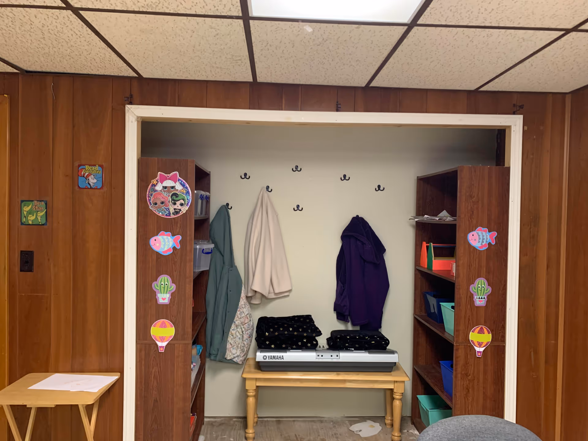 Coat closet area inside a facility with jackets, shelves, and a keyboard table.