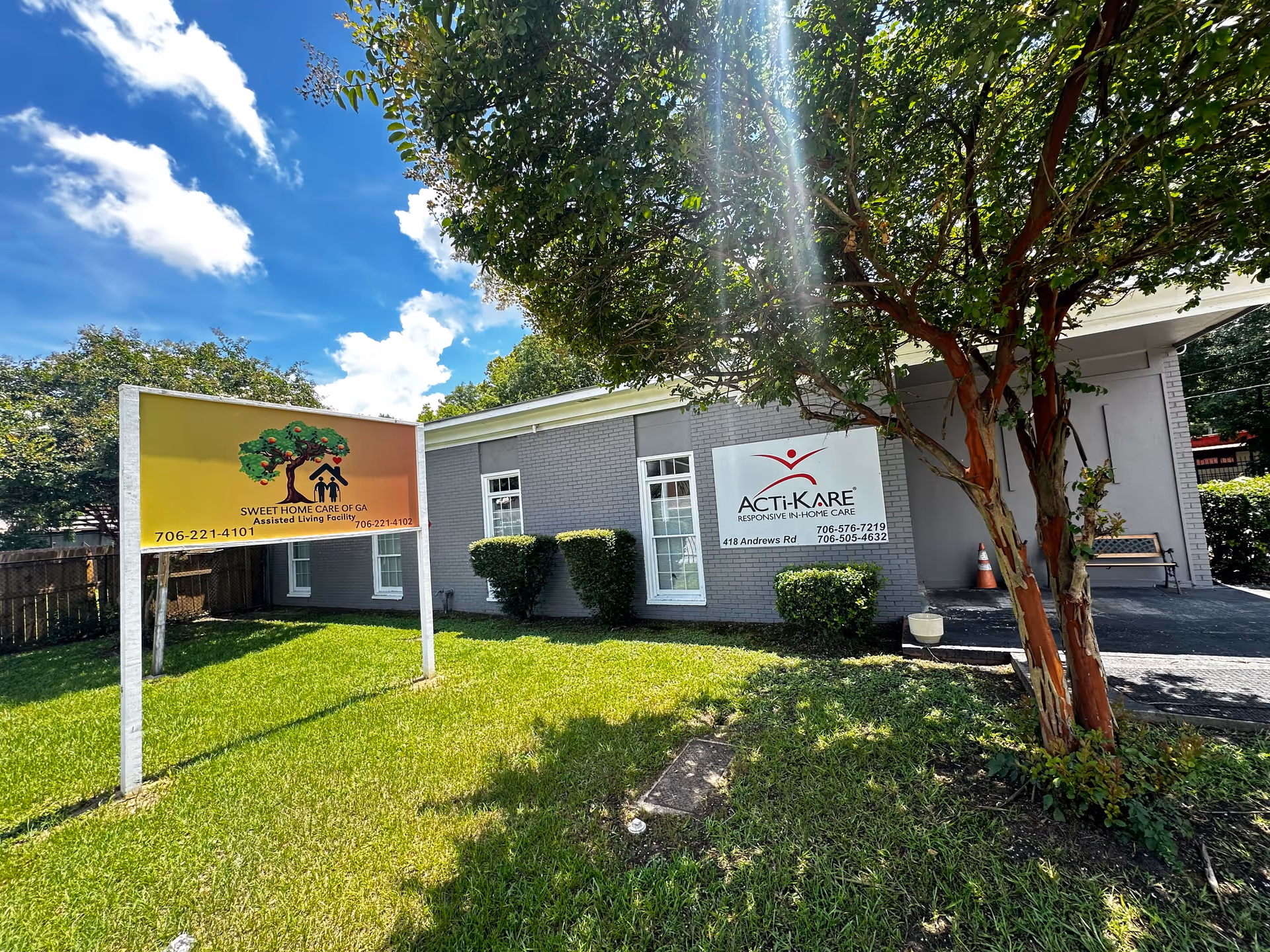Exterior view of a gray building with two signs and a green lawn.
