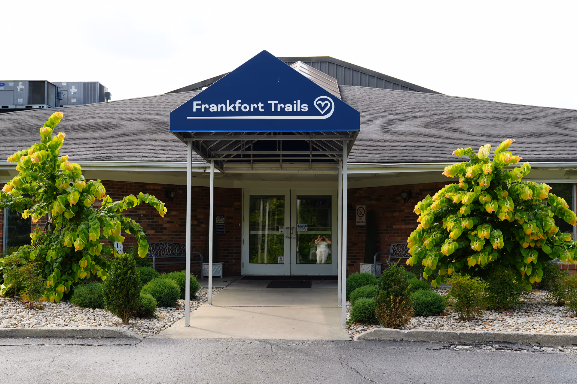 Front entrance of Frankfort Trails senior living facility with blue sign and landscaped sides.