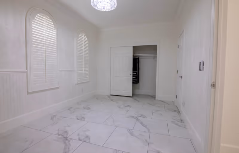Bright white interior room with marble tile floor, arched windows, and open closet.