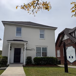 Two-story white building with a black front door and 'homeRN' sign beside the entrance.