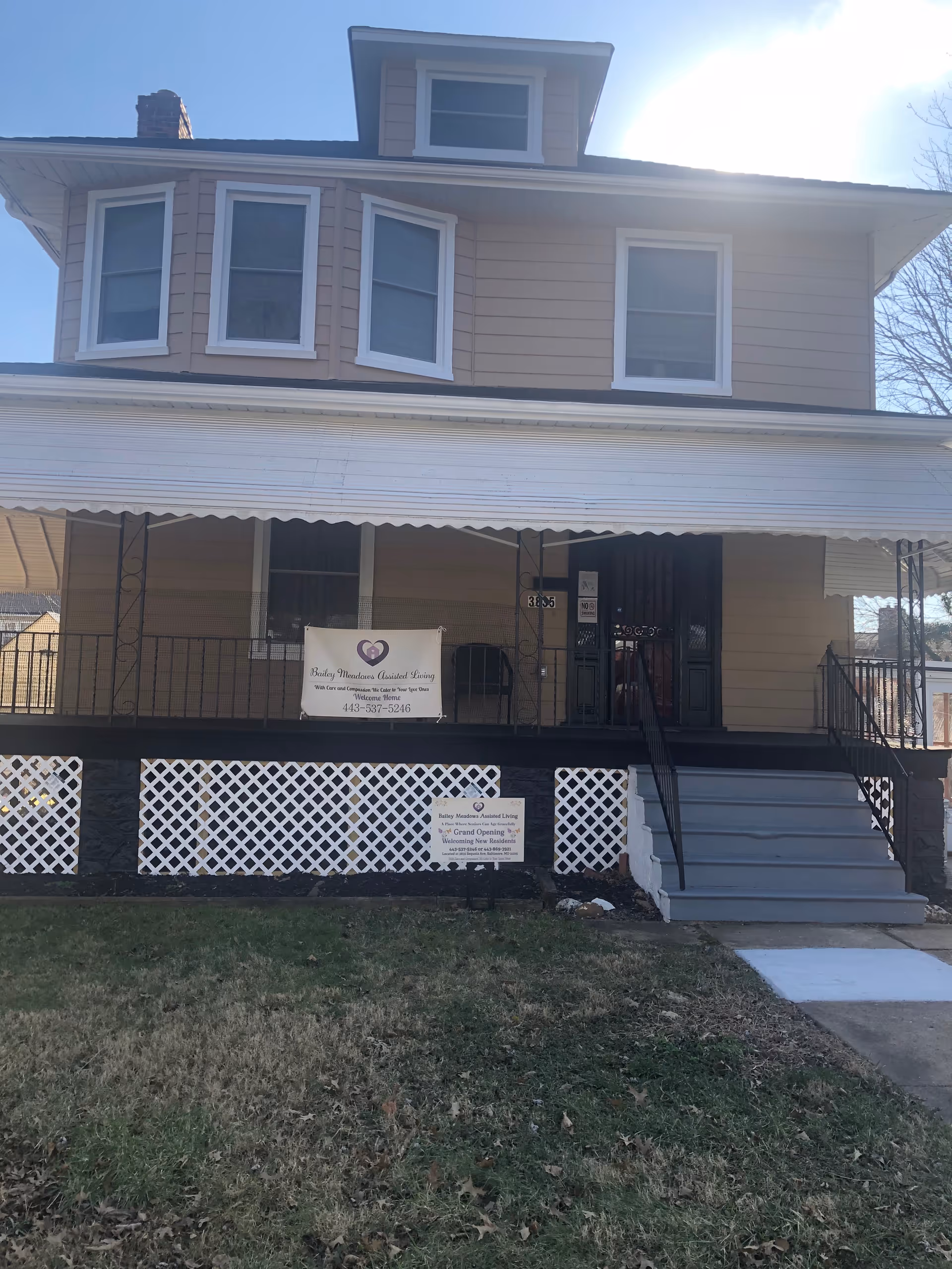Two-story beige senior living facility with a front porch and banners.