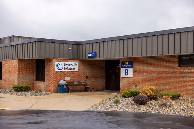 Brick exterior of a senior care facility with a Senior Life Solutions sign and landscaped entrance.
