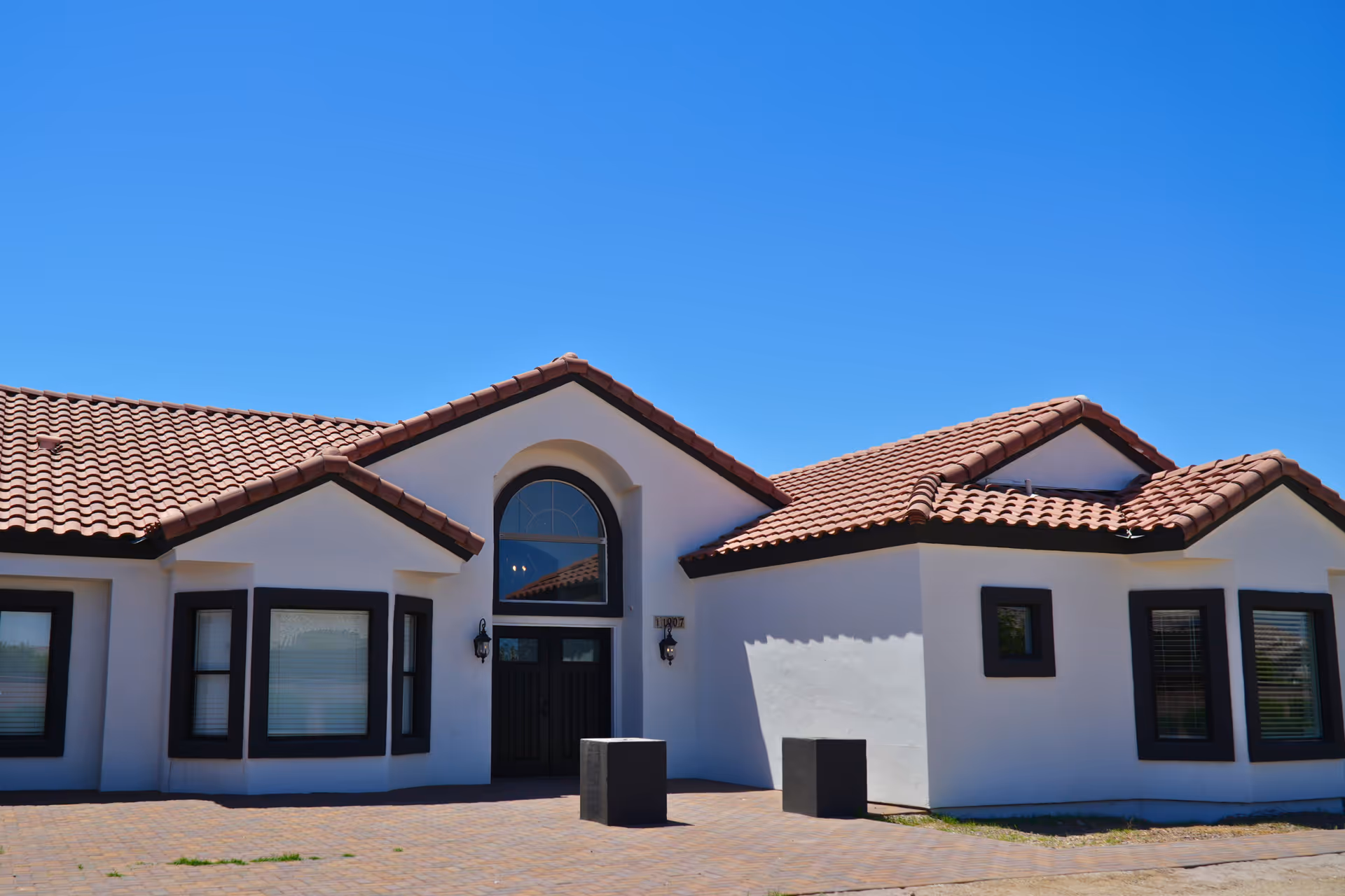 White stucco assisted living building with red-tiled roof and arched entrance window