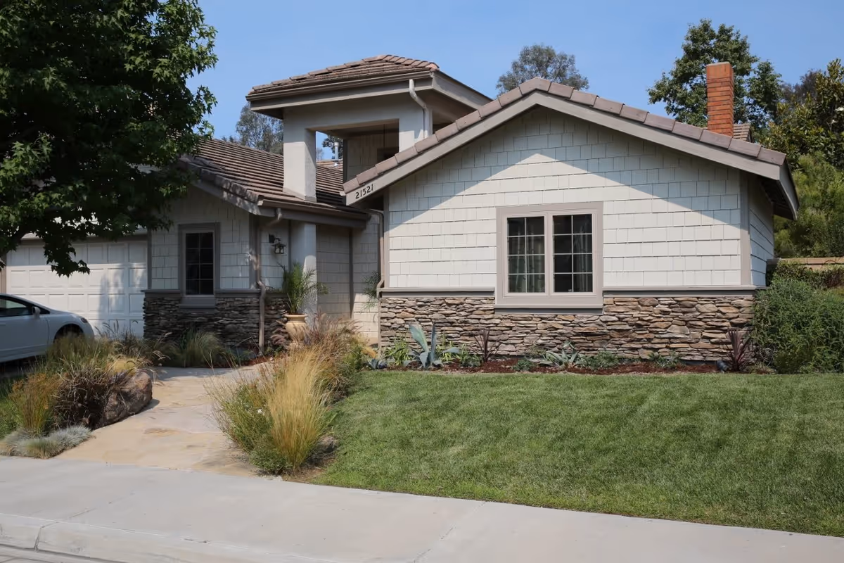 Front exterior of a modern house with stone accents and a manicured lawn.
