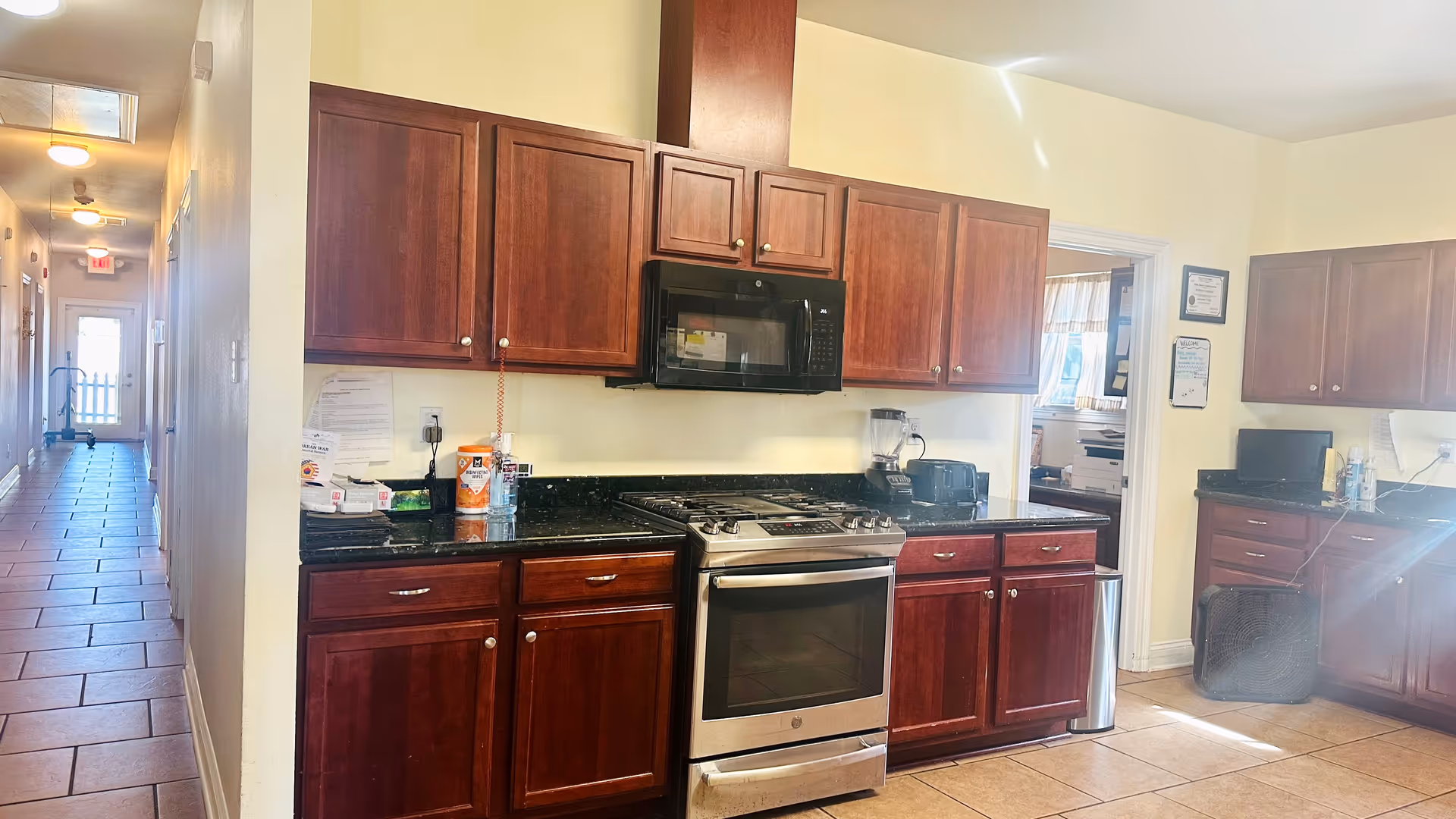 A well equipped kitchen in a senior residence with dark oak cabinets, stove, microwave, and countertops.