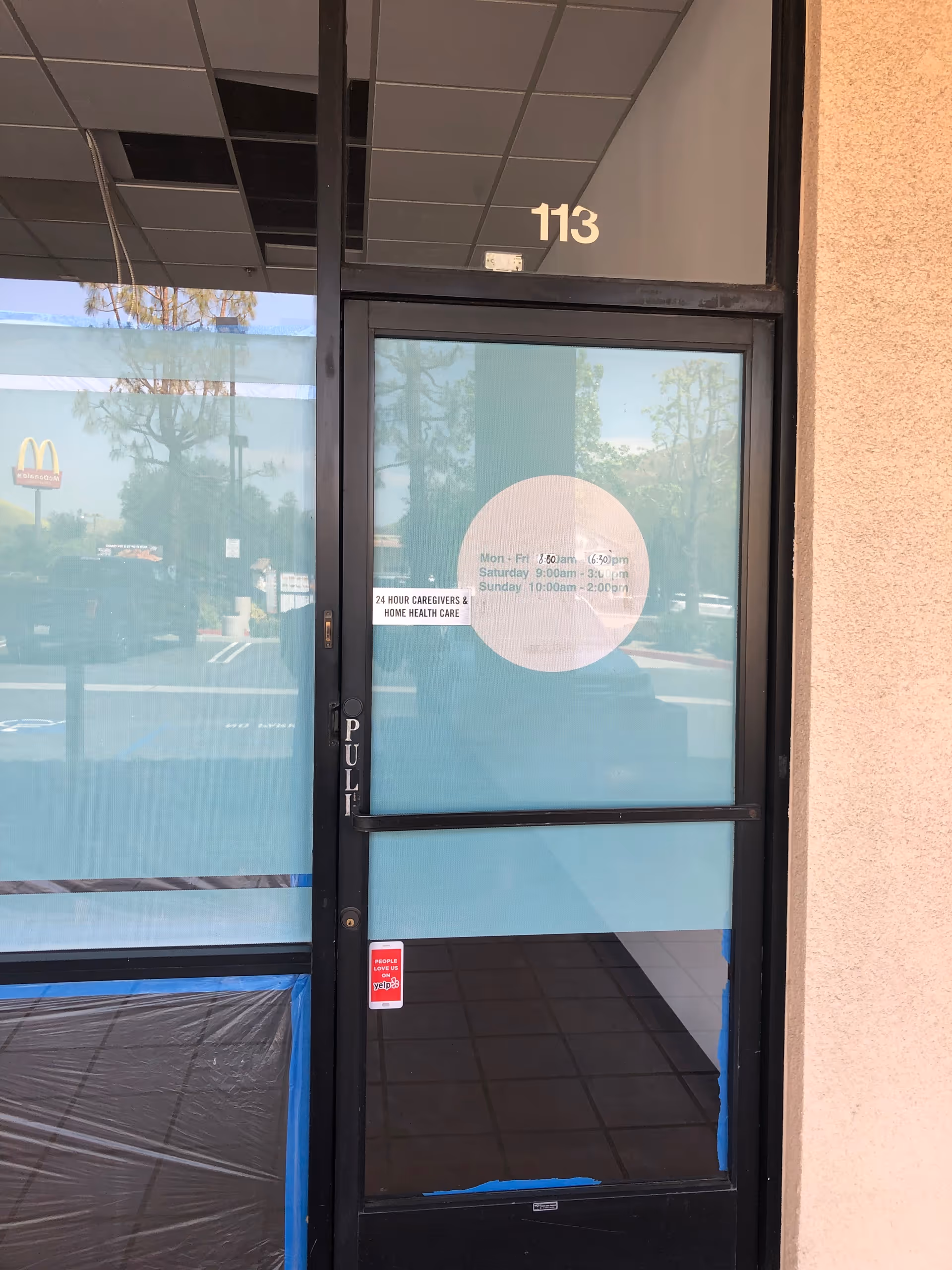 Glass entrance door labeled 113 with a 24 Hour Caregivers sticker.