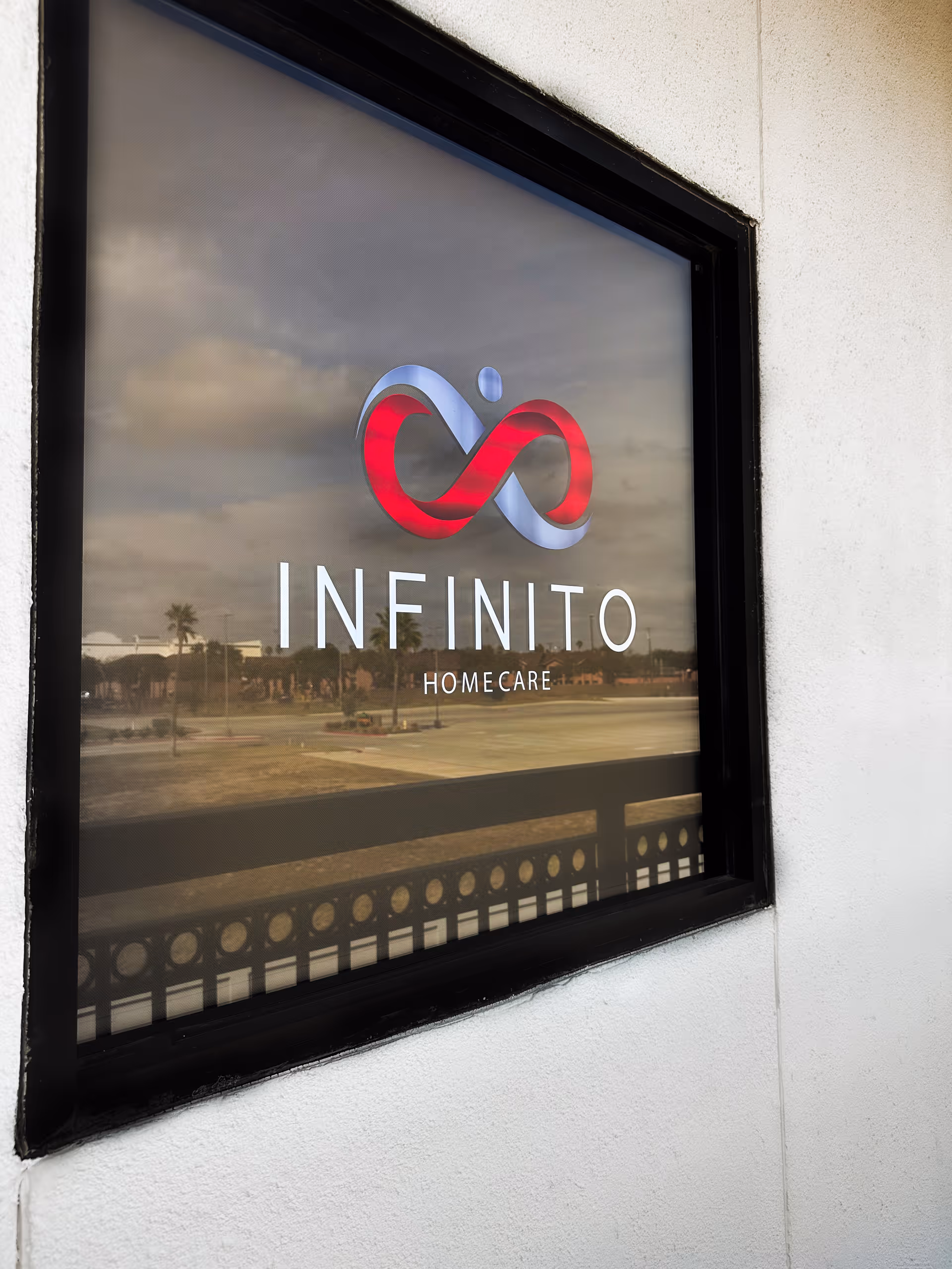 Exterior view of a window sign reading INFINITO HOMECARE on a white building