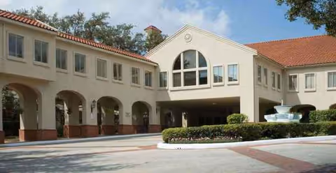 Front exterior view of Madison Estates with arches, driveway, and a central fountain.