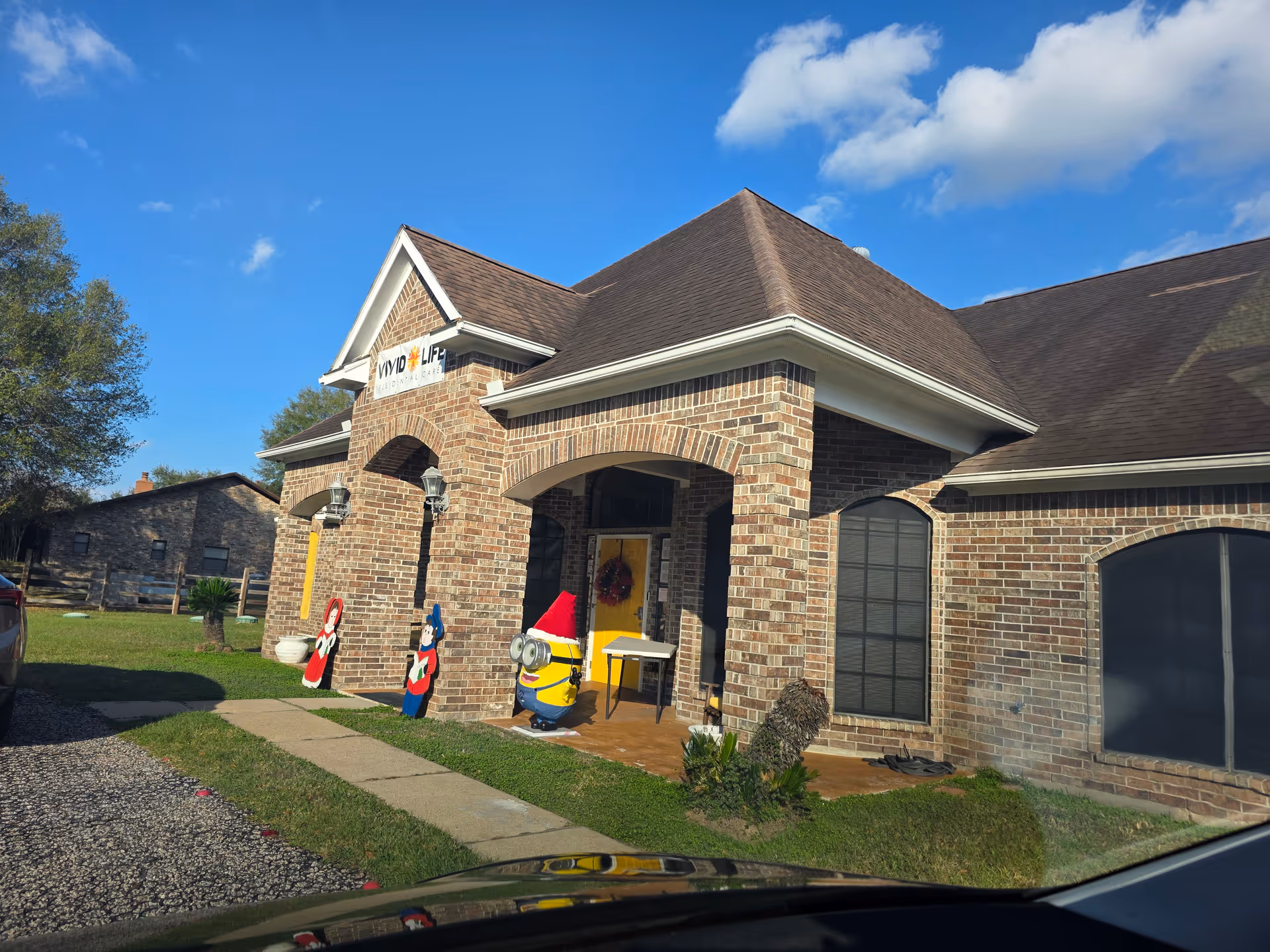 Front of brick senior living facility entrance with festive decorations and Vivid Life sign.