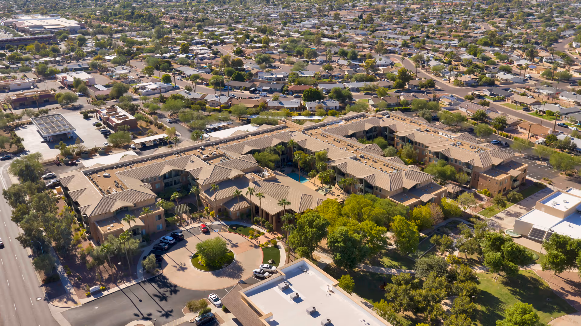 Aerial view of McDowell Village senior living facility surrounded by residential neighborhoods, showing multiple connected buildings with tan roofs, parking areas, trees, and nearby streets.